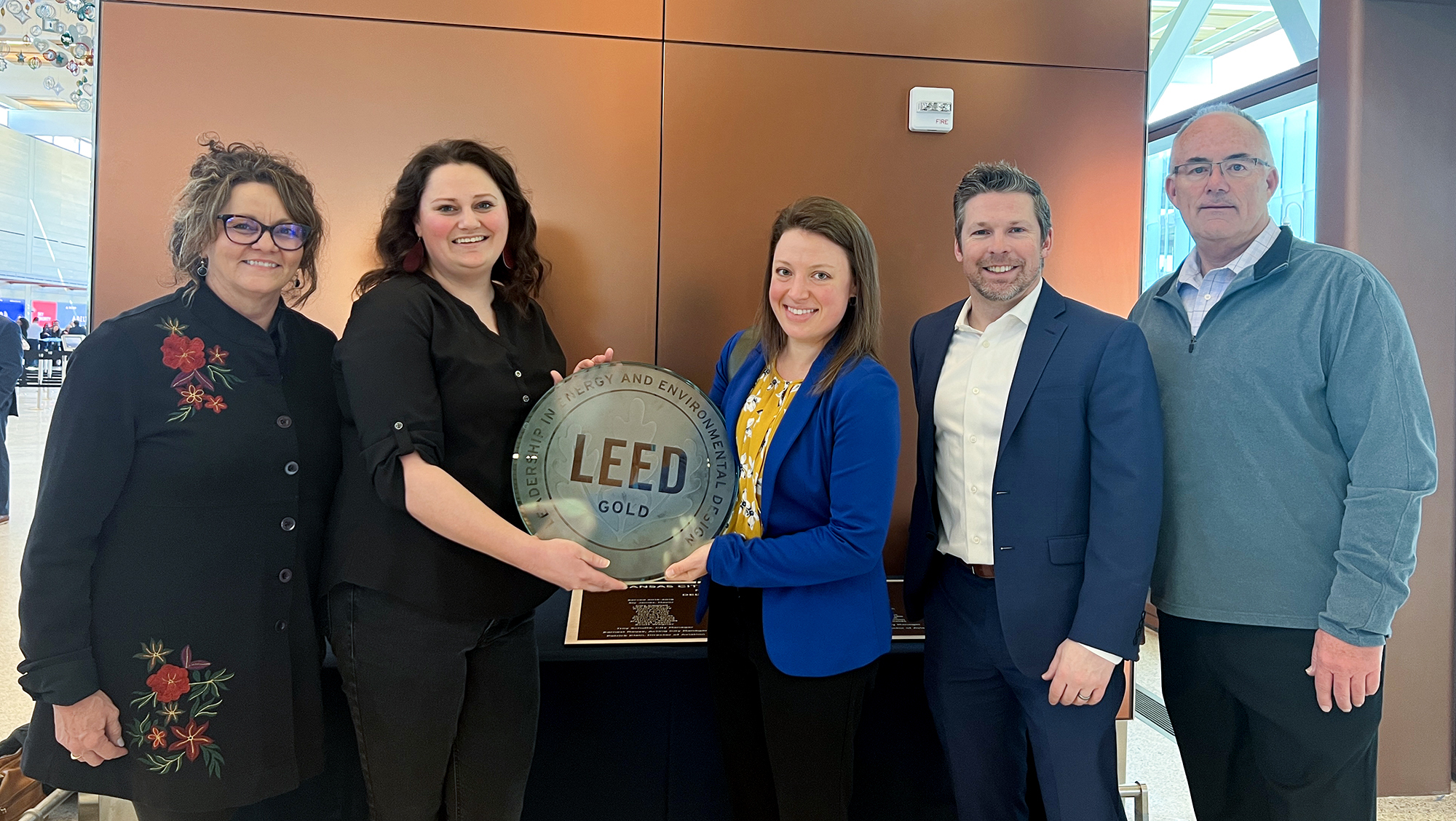 Coworkers holding a LEED Gold award for Kansas City International Airport